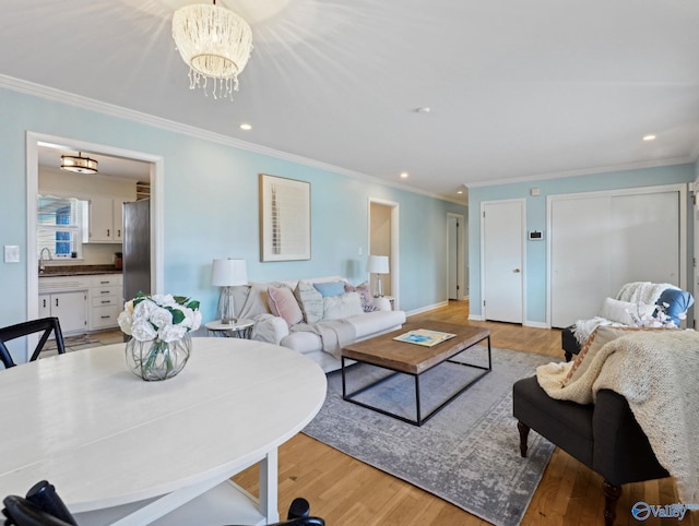 living room with light wood-type flooring, a chandelier, and ornamental molding