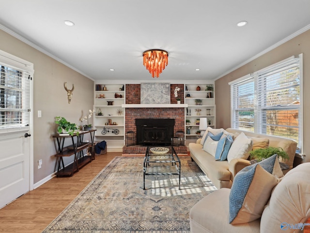 living room with a brick fireplace, built in features, crown molding, and light hardwood / wood-style floors