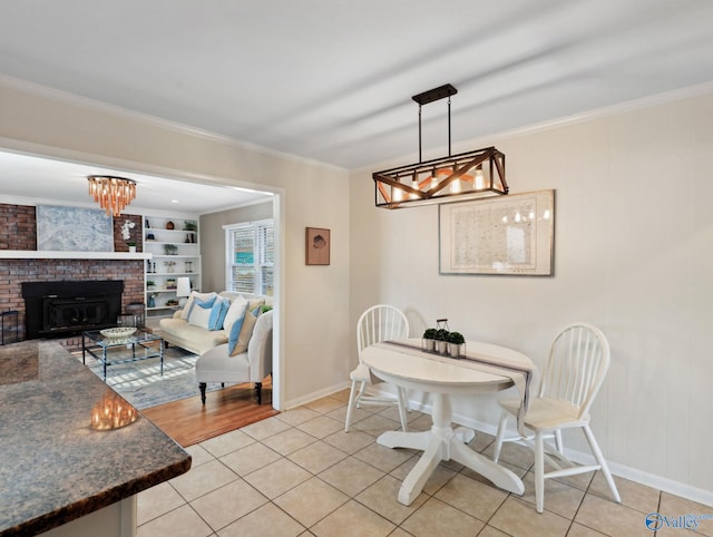 tiled dining area featuring an inviting chandelier, built in shelves, crown molding, and a fireplace