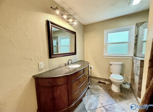 bathroom with toilet, a textured wall, vanity, and marble finish floor