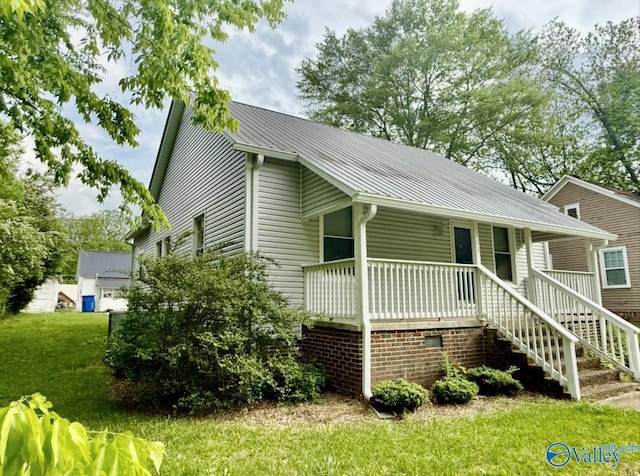 view of front of property with stairs, covered porch, metal roof, and a front yard