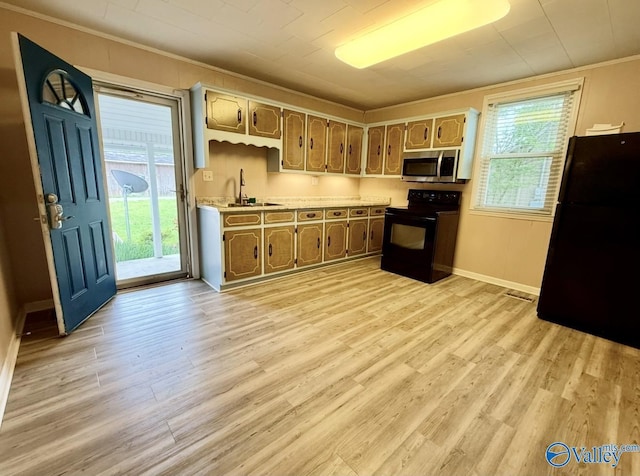 kitchen with light wood finished floors, a sink, black appliances, light countertops, and ornamental molding