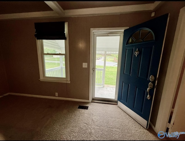 entrance foyer with visible vents, beam ceiling, carpet floors, and baseboards