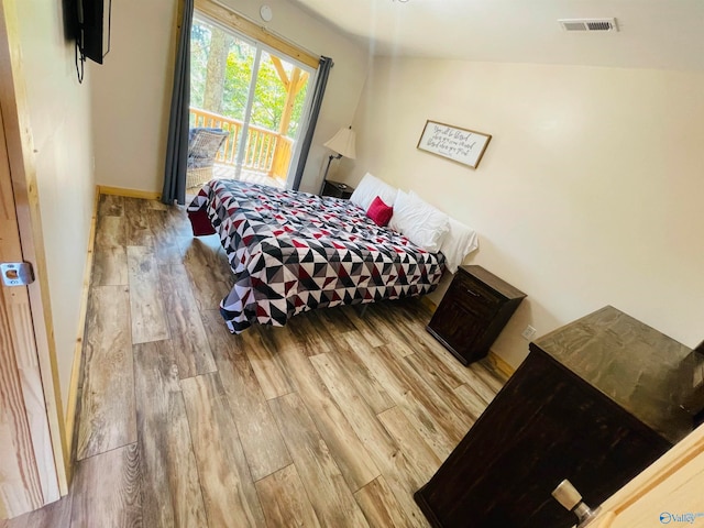 bedroom featuring vaulted ceiling, hardwood / wood-style flooring, and access to outside