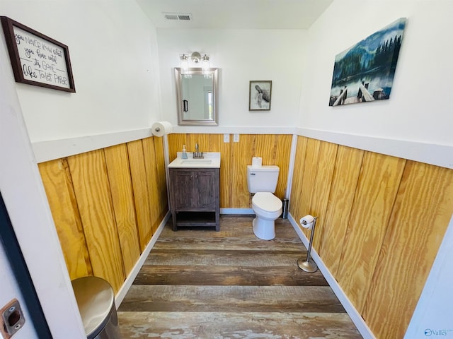 bathroom featuring vanity, wood-type flooring, toilet, and wood walls