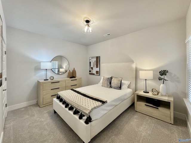 bedroom with visible vents, light carpet, and baseboards