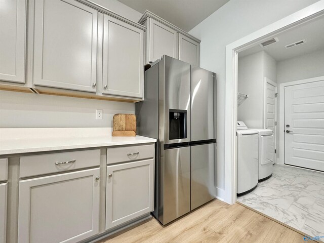 kitchen with visible vents, marble finish floor, gray cabinets, washer and clothes dryer, and stainless steel fridge