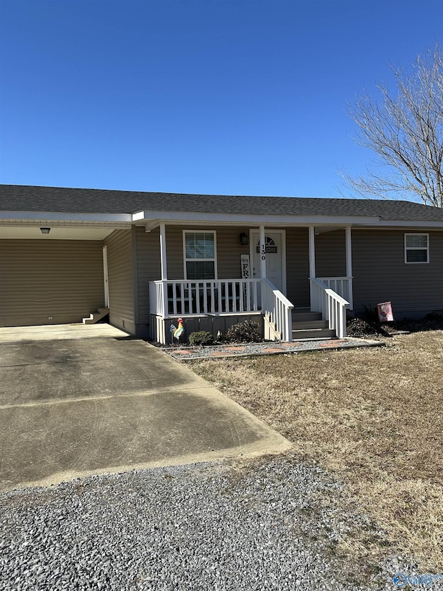 ranch-style house featuring covered porch and a carport