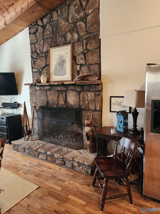 living room featuring a fireplace, beamed ceiling, and hardwood / wood-style floors