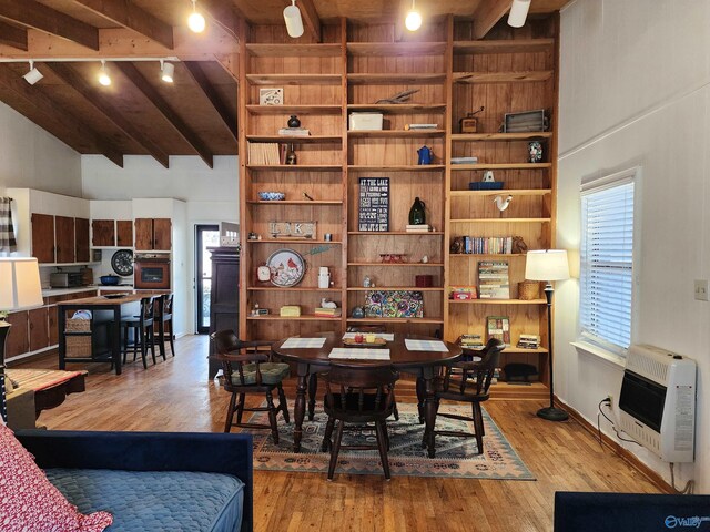 dining area with beam ceiling, heating unit, light hardwood / wood-style flooring, and high vaulted ceiling