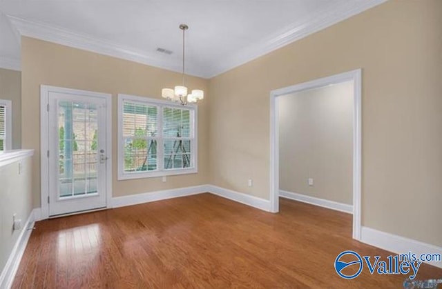 unfurnished dining area featuring hardwood / wood-style floors, crown molding, and a chandelier