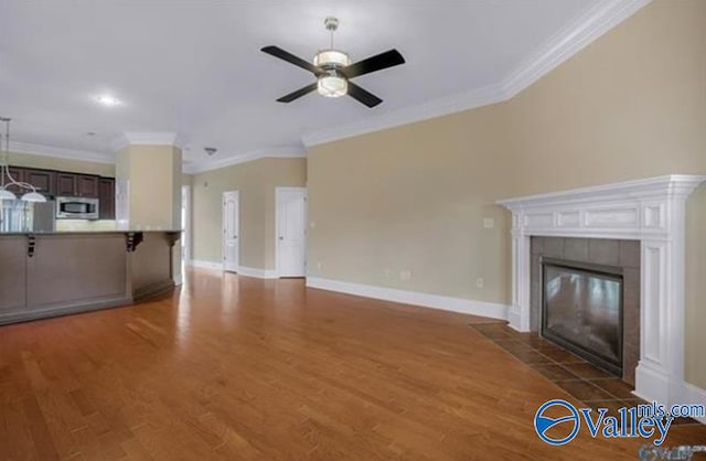 unfurnished living room featuring ceiling fan, dark hardwood / wood-style flooring, ornamental molding, and a fireplace