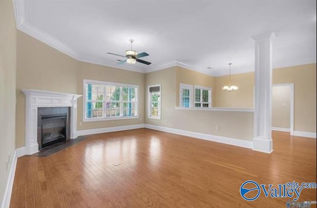 unfurnished living room with ceiling fan with notable chandelier, hardwood / wood-style flooring, ornate columns, and ornamental molding