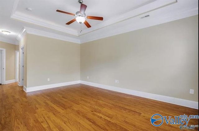 spare room featuring a tray ceiling, ceiling fan, wood-type flooring, and ornamental molding