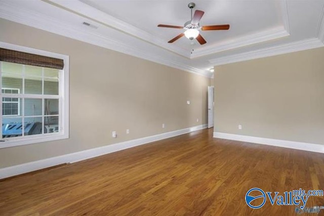 spare room with hardwood / wood-style floors, a tray ceiling, ceiling fan, and ornamental molding