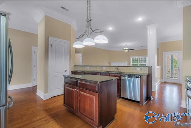 kitchen with appliances with stainless steel finishes, dark hardwood / wood-style flooring, ornamental molding, pendant lighting, and a center island