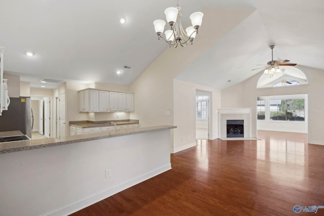 kitchen with baseboards, wood finished floors, freestanding refrigerator, hanging light fixtures, and a fireplace