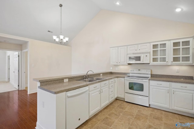 kitchen with a peninsula, white appliances, a sink, white cabinets, and glass insert cabinets