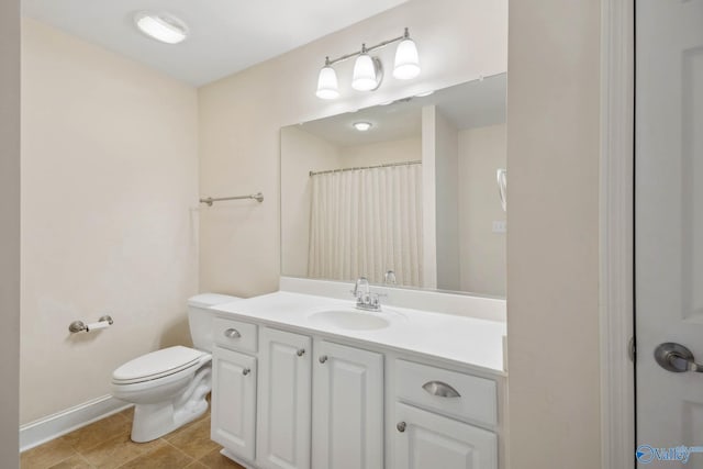 bathroom with toilet, tile patterned floors, baseboards, and vanity