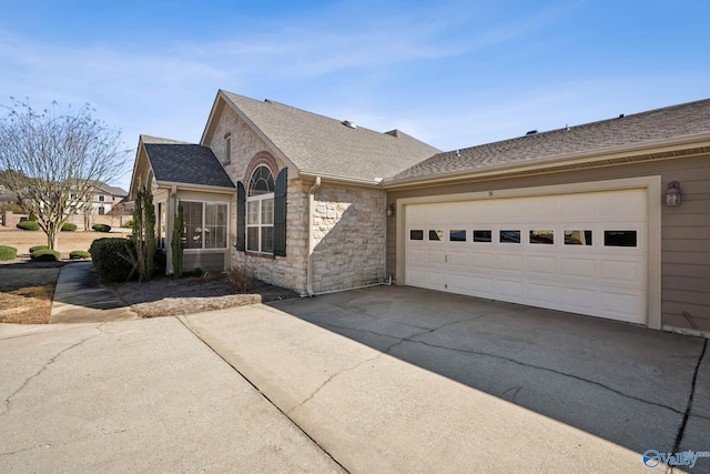 single story home with driveway, stone siding, and roof with shingles