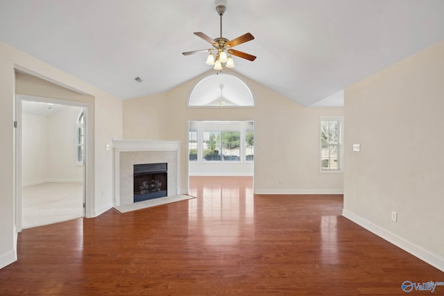 unfurnished living room featuring vaulted ceiling, plenty of natural light, a tiled fireplace, and wood finished floors