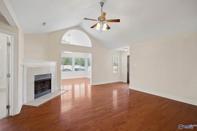 unfurnished living room with high vaulted ceiling, a tile fireplace, wood finished floors, a ceiling fan, and baseboards