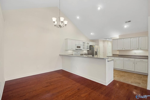 kitchen featuring stainless steel fridge, visible vents, white cabinets, white microwave, and a peninsula