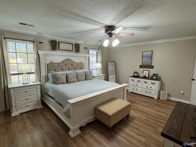 bedroom featuring ceiling fan, dark wood-type flooring, multiple windows, and crown molding