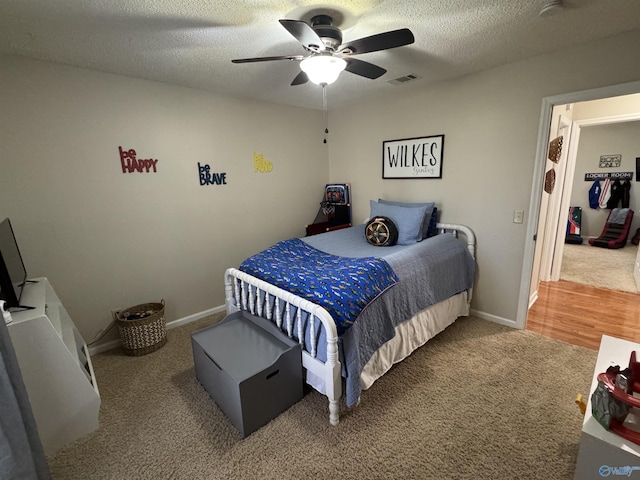 carpeted bedroom featuring ceiling fan and a textured ceiling