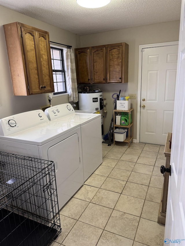 washroom with a textured ceiling, washer and clothes dryer, cabinets, electric water heater, and light tile patterned flooring