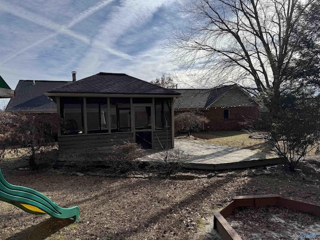 back of house featuring a playground, a wooden deck, and a sunroom