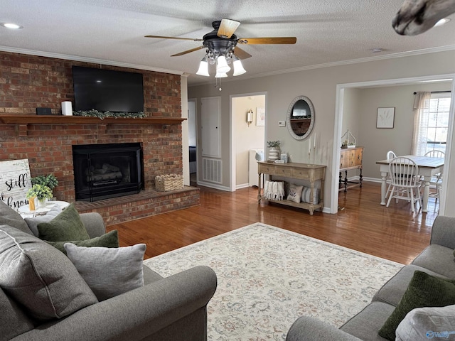 living room with crown molding, hardwood / wood-style floors, a textured ceiling, and a fireplace