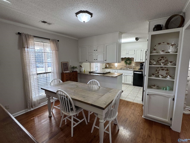 dining area featuring hardwood / wood-style flooring, sink, a textured ceiling, and crown molding