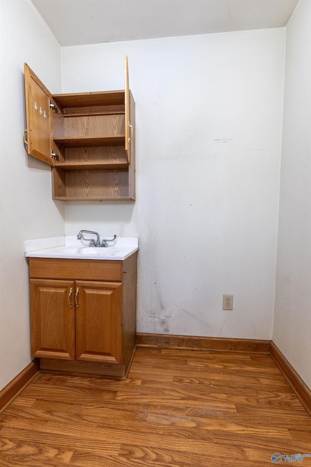 interior space featuring wood finished floors, baseboards, and a sink