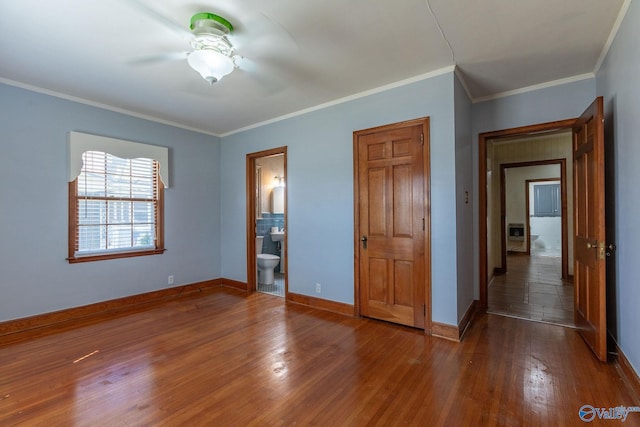 unfurnished bedroom with crown molding, ceiling fan, baseboards, wood finished floors, and ensuite bath