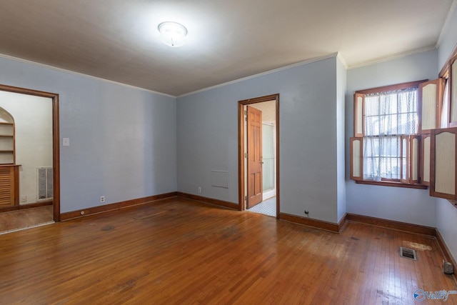 spare room featuring visible vents, ornamental molding, baseboards, and hardwood / wood-style floors