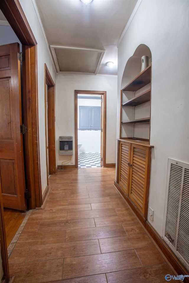 corridor featuring hardwood / wood-style floors, heating unit, baseboards, visible vents, and ornamental molding