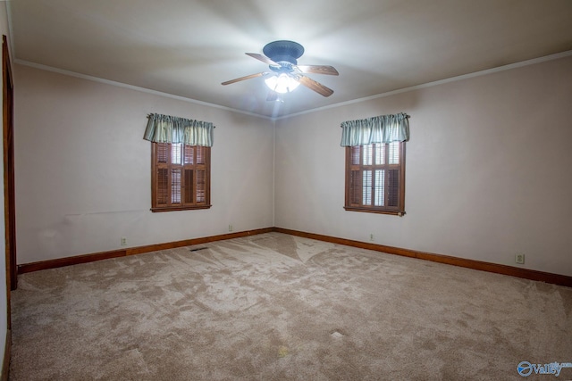 carpeted empty room with baseboards, ceiling fan, and crown molding