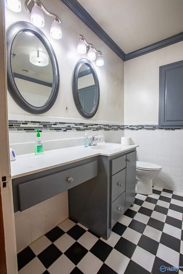 bathroom with tile patterned floors, toilet, ornamental molding, tile walls, and vanity