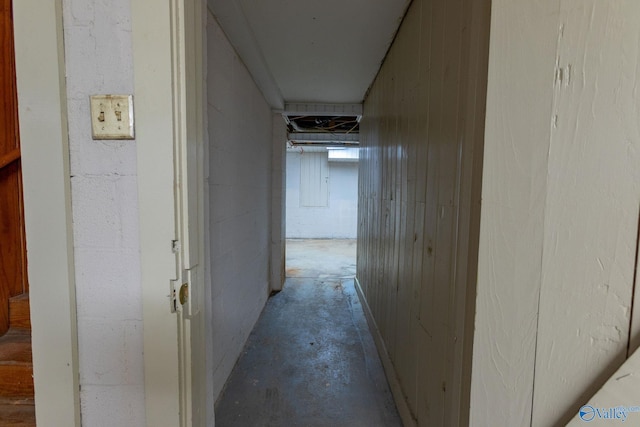 corridor featuring unfinished concrete floors and concrete block wall