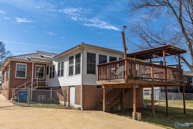 rear view of house featuring a deck, fence, stairway, a sunroom, and brick siding