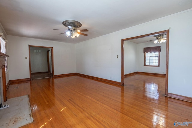 unfurnished living room with baseboards, a fireplace with flush hearth, light wood-type flooring, ornamental molding, and a ceiling fan