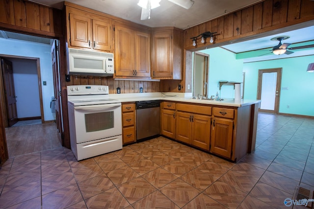 kitchen featuring white appliances, light countertops, a ceiling fan, and a sink