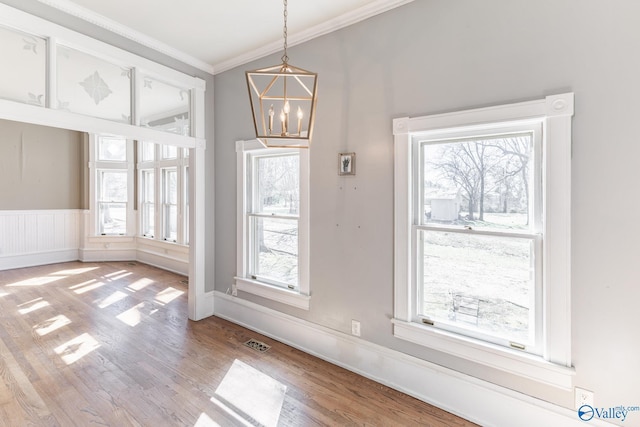 unfurnished dining area with a wealth of natural light, visible vents, light wood-style flooring, and crown molding