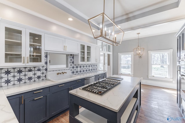 kitchen featuring a sink, tasteful backsplash, white cabinetry, stainless steel appliances, and crown molding