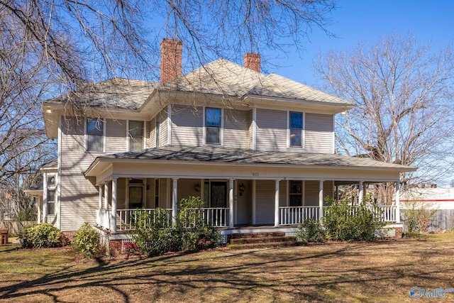 farmhouse inspired home with a front yard, covered porch, and a chimney