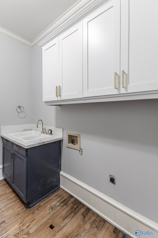 laundry room featuring light wood-style flooring, ornamental molding, a sink, cabinet space, and hookup for a washing machine