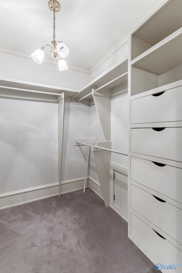 spacious closet featuring a chandelier and dark carpet