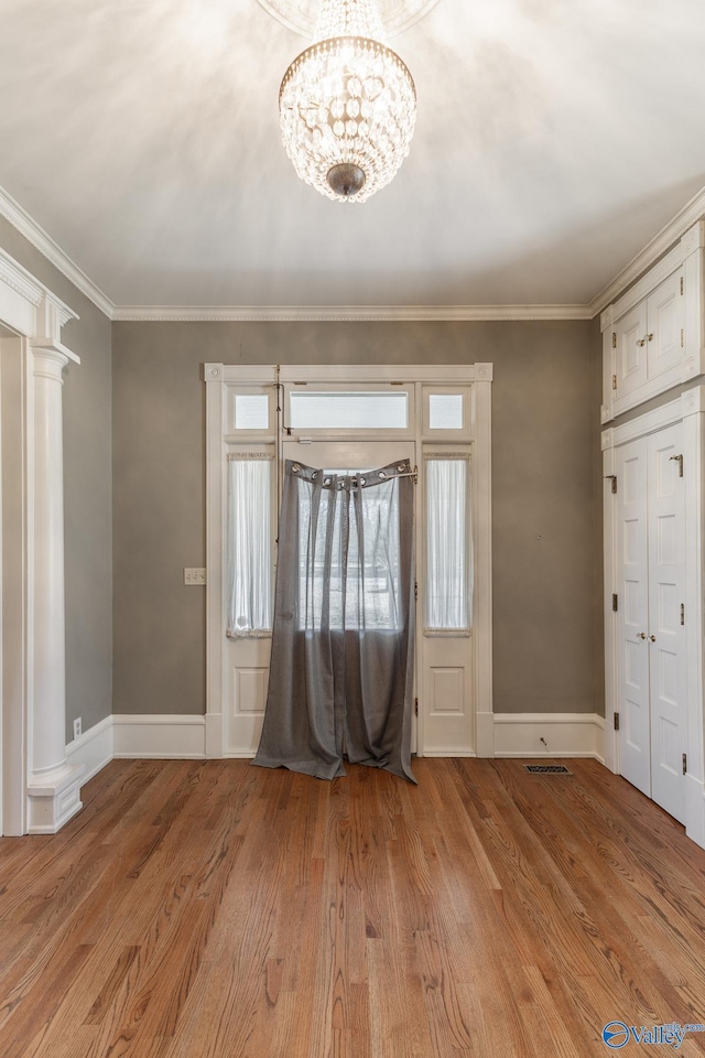 entrance foyer featuring light wood-style flooring, crown molding, baseboards, and decorative columns