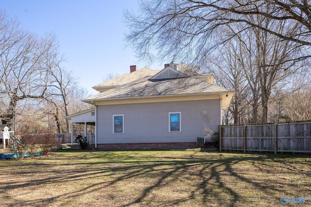 view of side of home with cooling unit, fence, a chimney, a playground, and a lawn